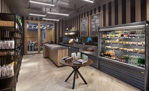 Een modern koffietent interieur met een toonbank, planken vol koffiebonen en een presentatie van flessen drank.