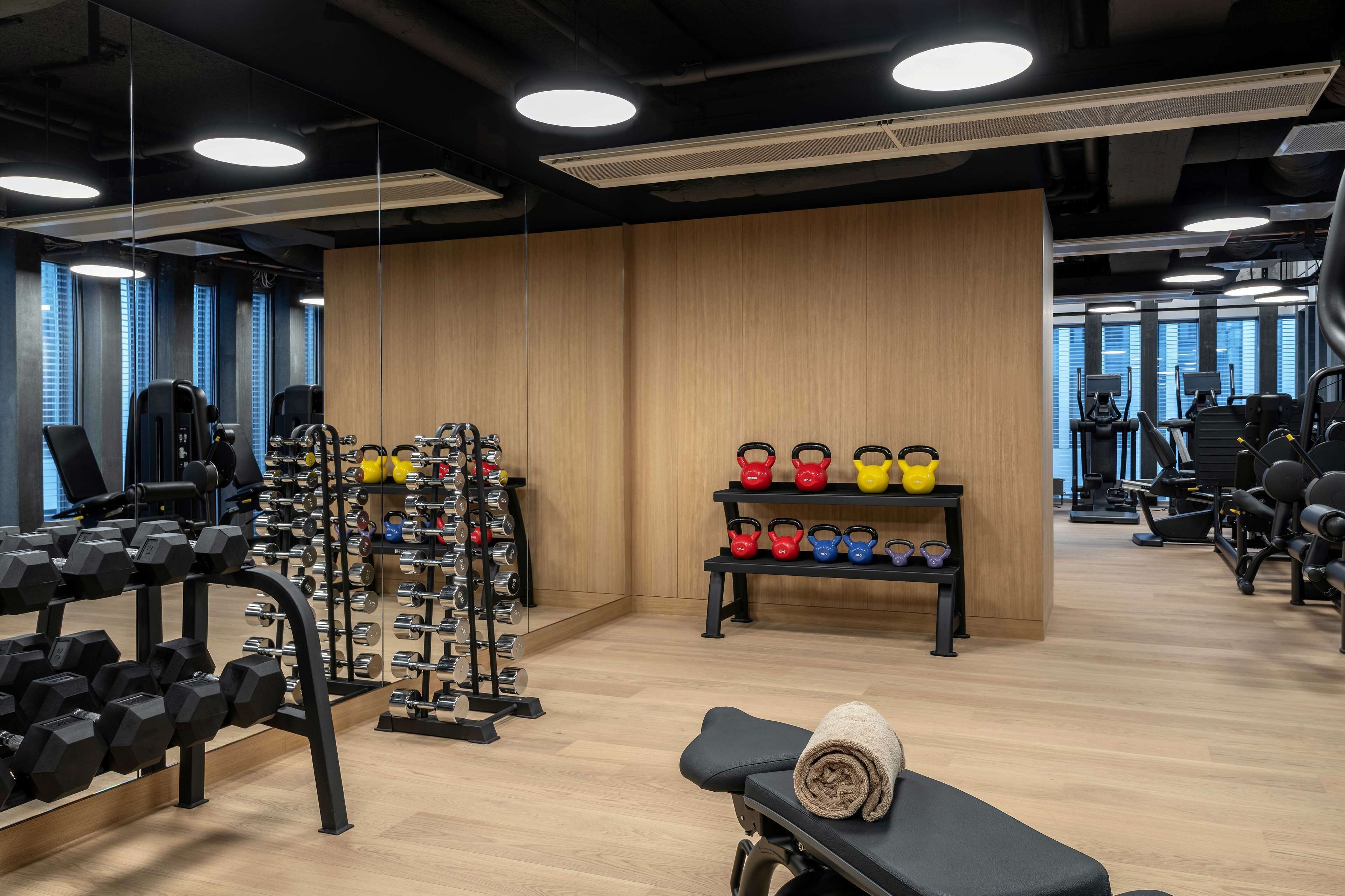 A gym with weightlifting equipment, kettlebells, and exercise machines.