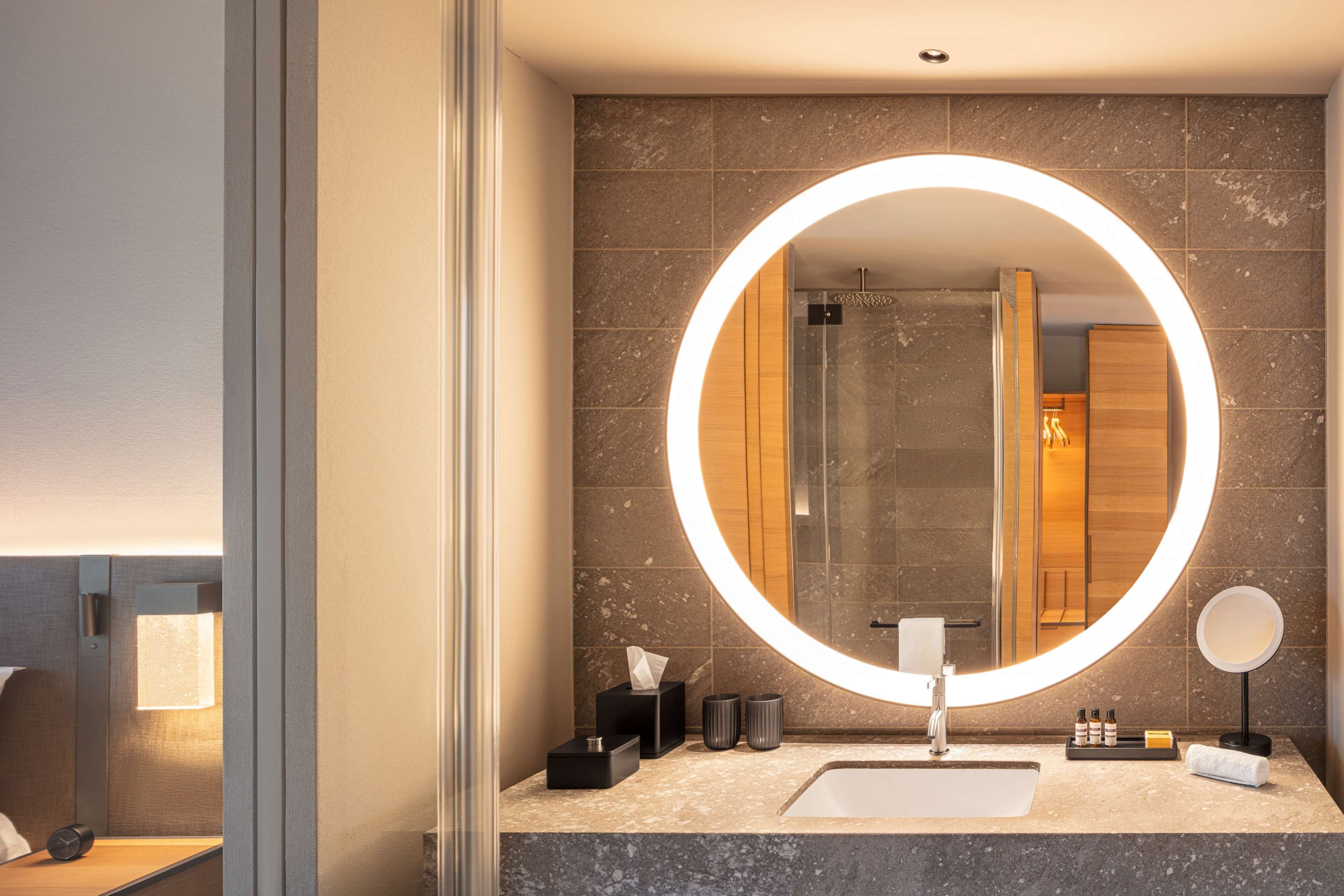 A modern bathroom with a large mirror, a sink, and a shower area.