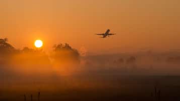 Um avião voando sobre uma paisagem durante o nascer ou pôr do sol.