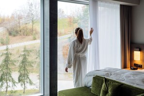 A room with a large window, a bed with green bedding, and a bedside table with a lamp. - Hyatt Regency Zurich Airport The Circle (Kloten)