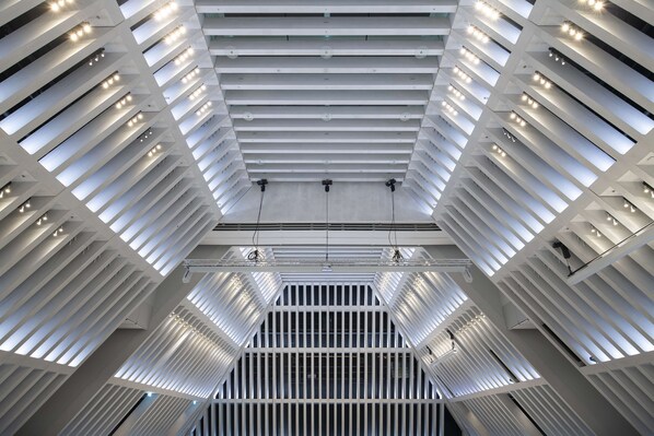 A modern architectural interior with a geometric ceiling design and linear lighting fixtures. - Hyatt Regency Zurich Airport The Circle (Kloten)