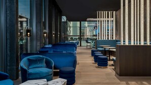 Un espace lounge moderne avec des sièges bleus, une table basse en marbre et un comptoir d’accueil en bois.