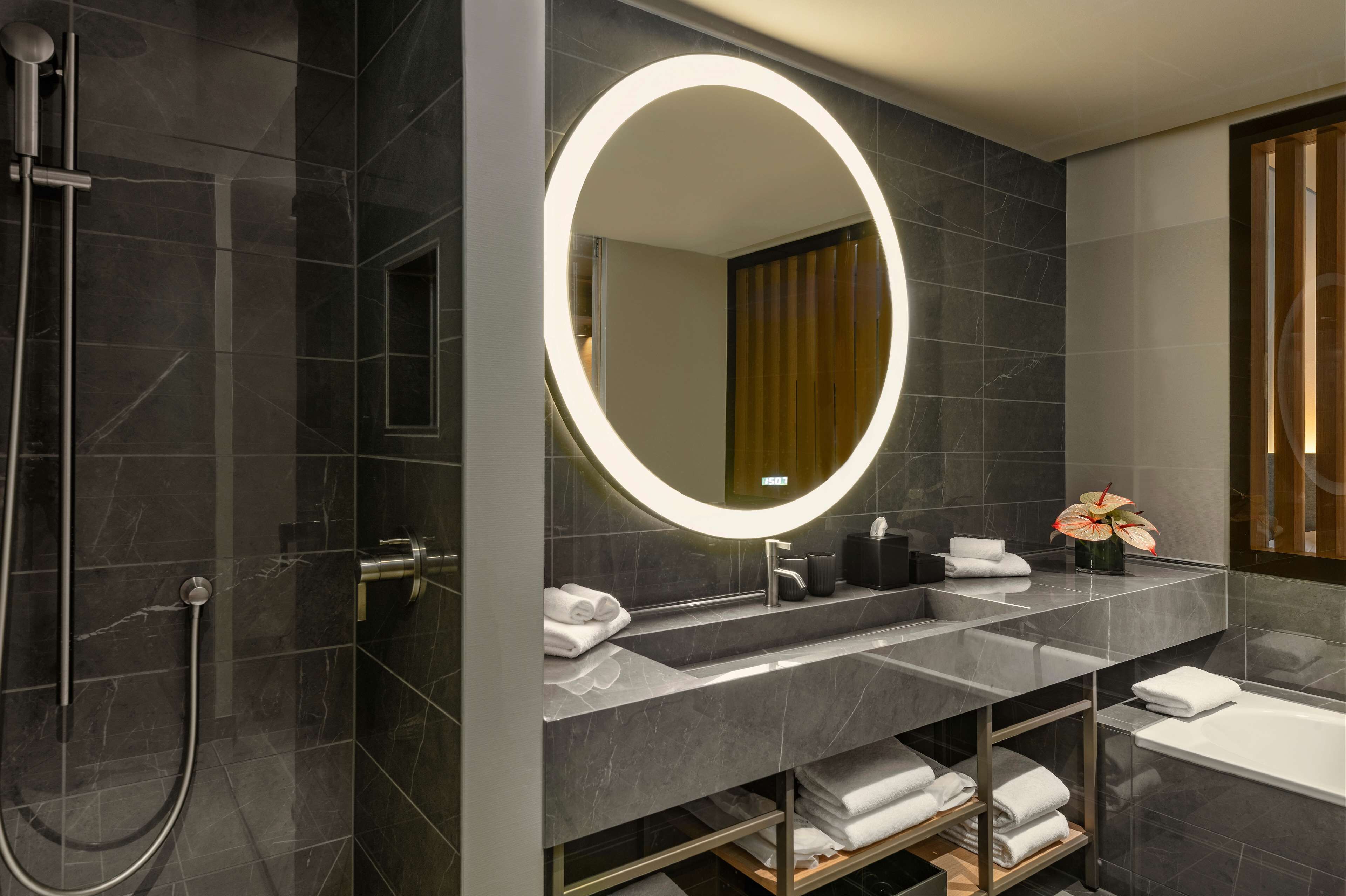 Un baño moderno con un espejo grande, lavamanos dobles, ducha y bañera.