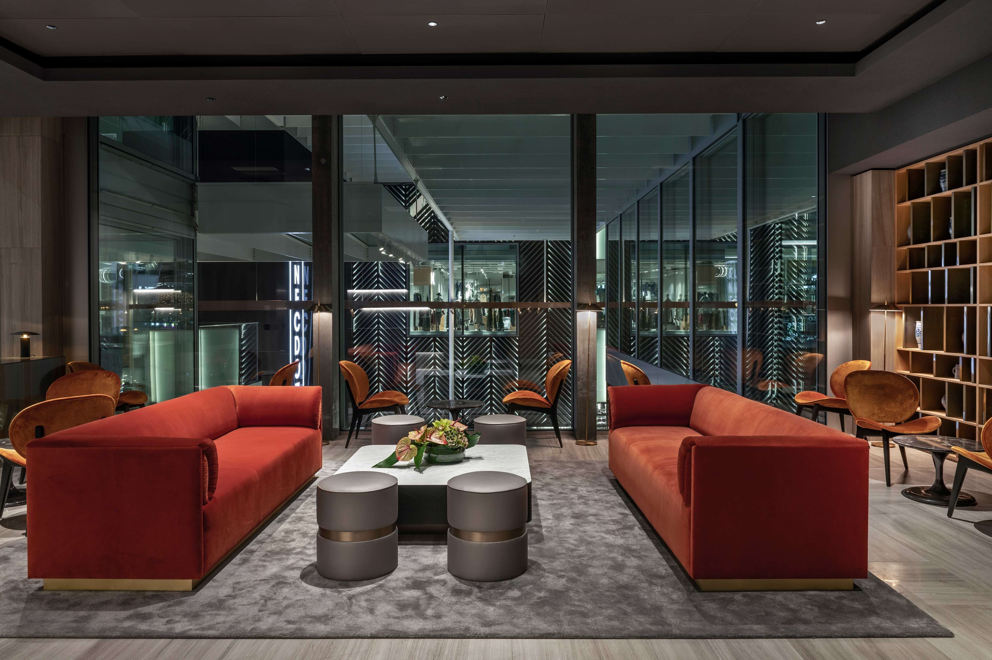 Ein modernes Interieur mit zwei roten Sofas, einem Couchtisch in der Mitte und einem Bücherregal.