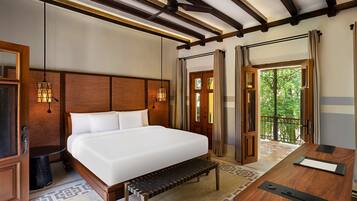 A bedroom with a large bed, wooden headboard, bedside lamps, and a view of the outdoors through an open door.