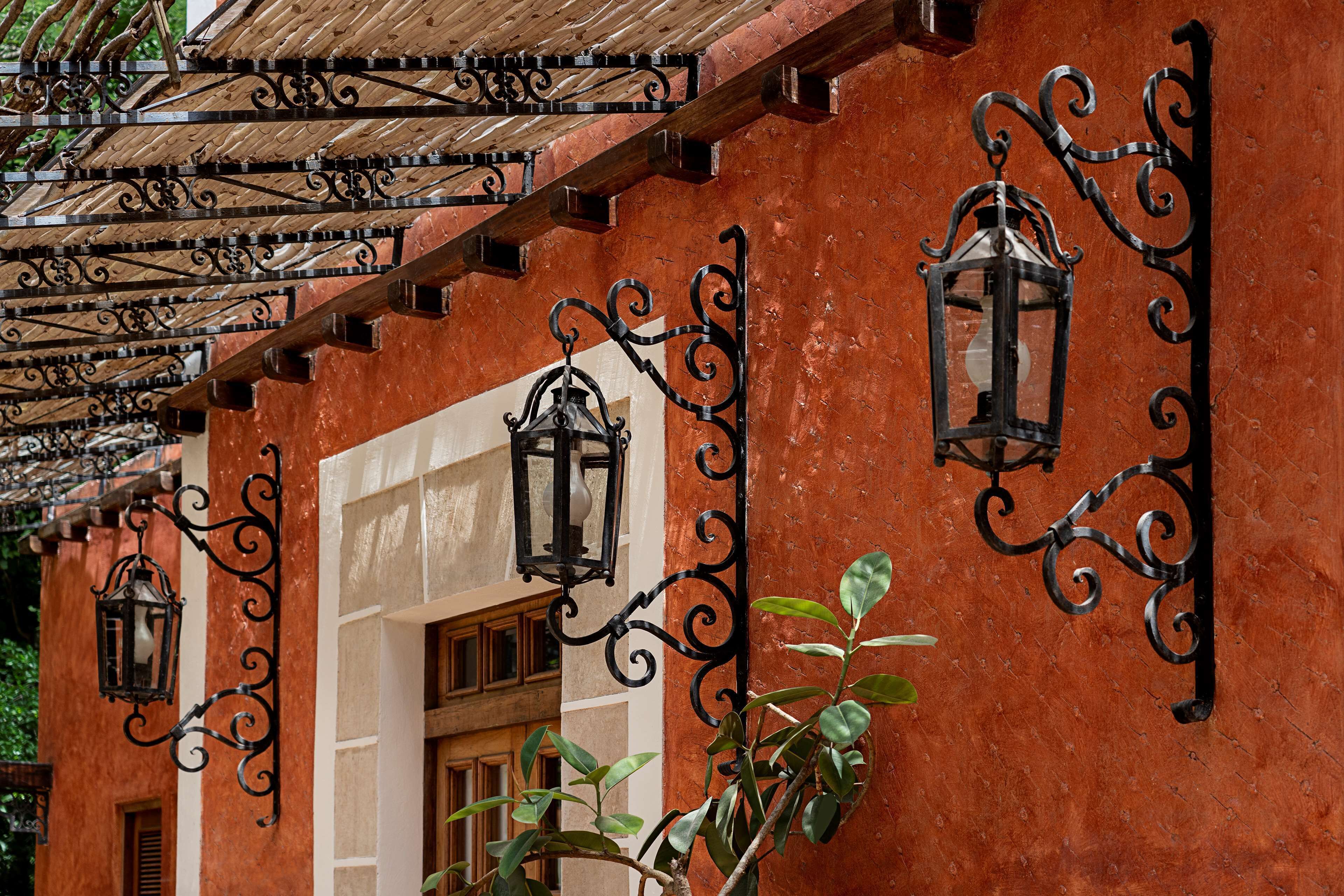 A building with wrought iron lanterns and a wooden pergola.