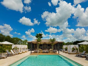 A poolside area with lounge chairs, a bar, and a covered seating area under a clear blue sky. - Hacienda Xcanatun, Angsana Heritage Collection (Mérida)