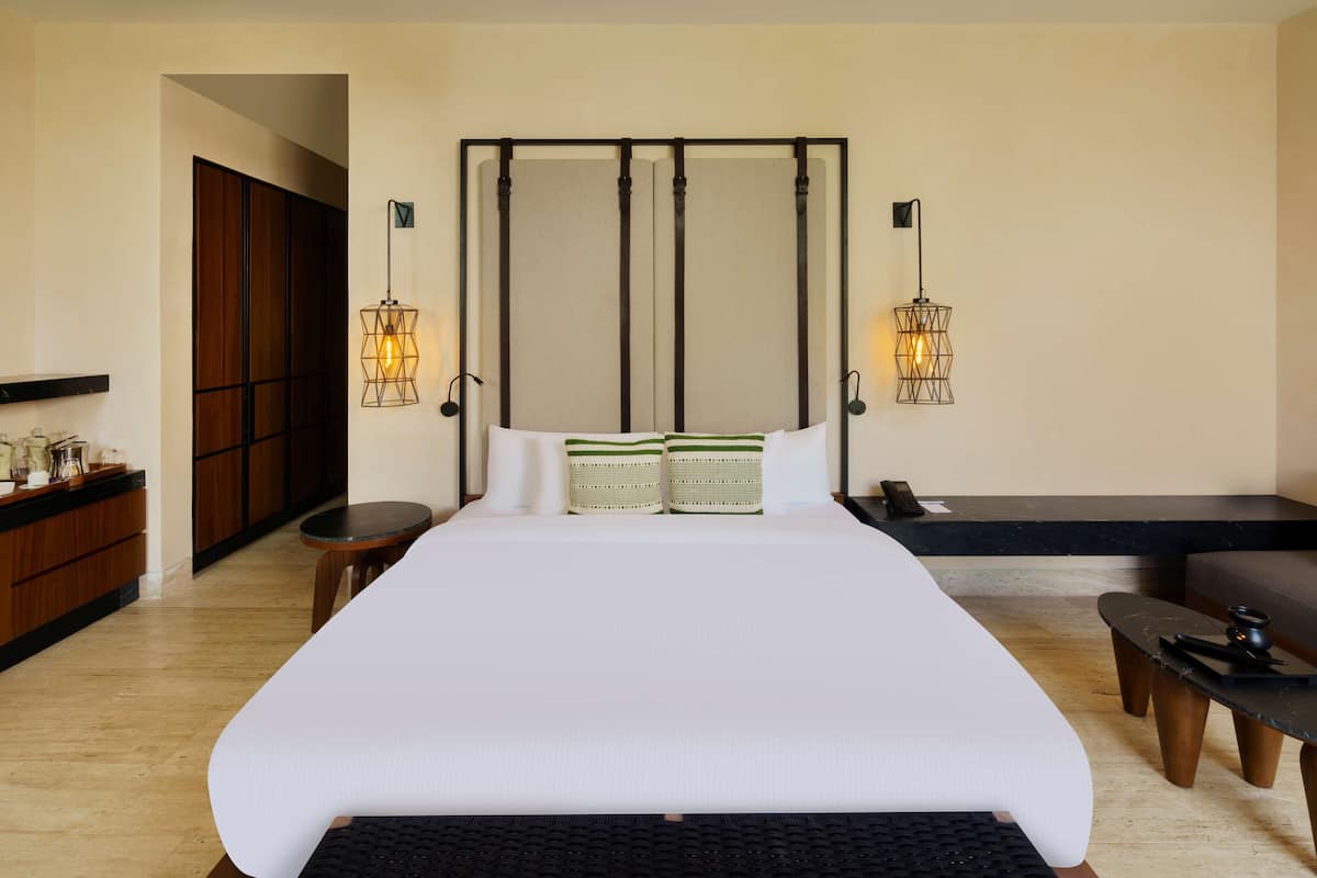 A spacious bedroom with a large bed, bedside tables, a desk, and a wardrobe.