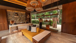A modern interior with a stone wall, wooden furniture, and a large window overlooking greenery. - Hacienda Xcanatun, Angsana Heritage Collection (Mérida)
