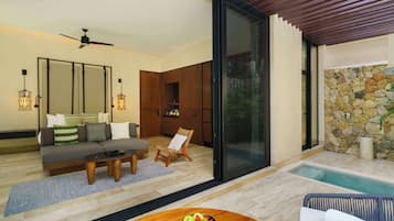 Sala de estar moderna com sofá, mesa de centro e mesa de jantar com frutas. Há uma porta de vidro que dá para uma área de piscina com parede de pedra.