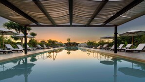 A pool area with lounge chairs and umbrellas, surrounded by greenery, under a shaded pergola. - Hacienda Xcanatun, Angsana Heritage Collection (Mérida)