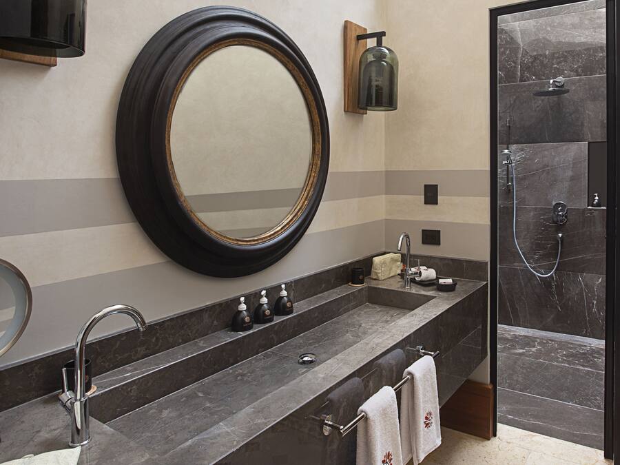 Un baño moderno con un espejo grande, un lavamanos con varios grifos y una zona de ducha.
