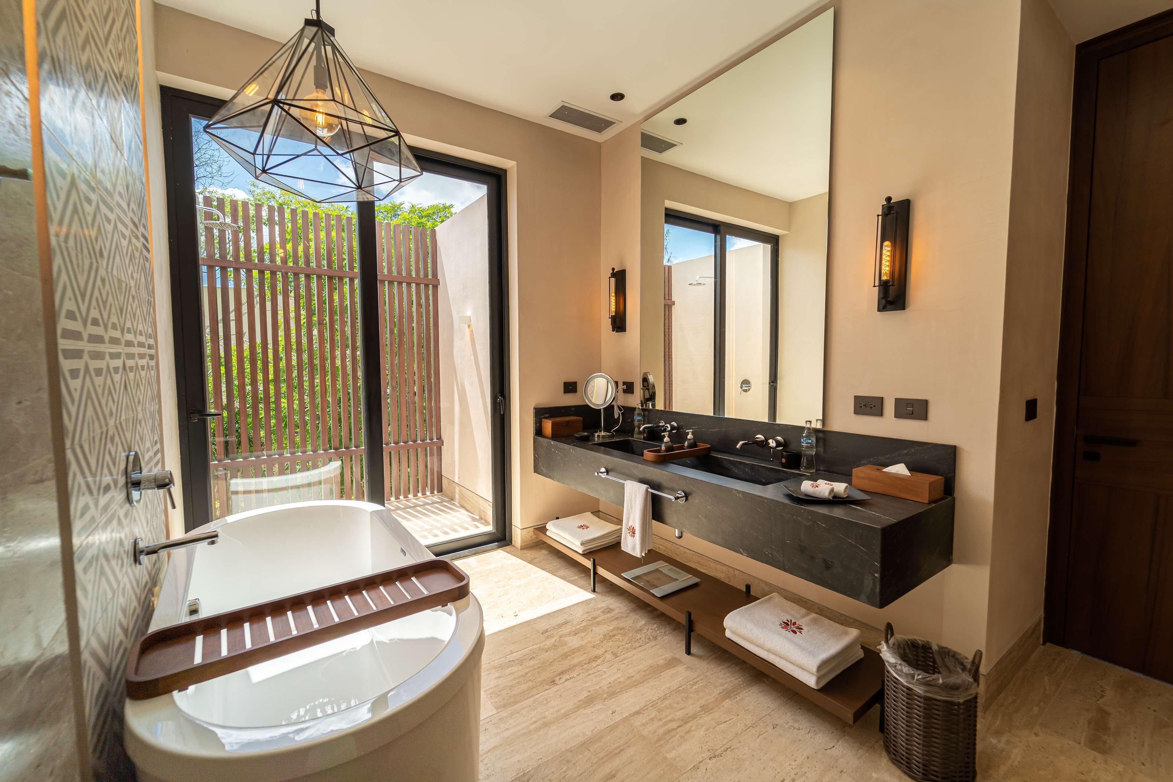 A modern bathroom with a freestanding bathtub, a large mirror, and a dark countertop sink.