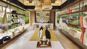 A modern hotel lobby with a central reception desk, wooden flooring, and large windows offering a view of greenery. - Hacienda Xcanatun, Angsana Heritage Collection (Mérida)