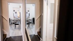 A hallway leading to a dining area with a table and chairs. - Stay Comfortable- New and stylish holiday home (Burslem)