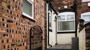 A narrow brick alleyway with a metal gate and steps leading to a door. - Stay Comfortable- New and stylish holiday home (Burslem)