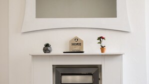 A fireplace with a mirror above it, a small sign that says "HOME Sweet Home," and a potted plant. - Stay Comfortable- New and stylish holiday home (Burslem)