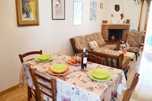 A dining area with a table set for four, chairs, a sofa, and a fireplace.