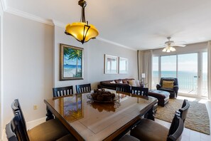 Relax in this spacious living area with a large dining table and comfortable seating, offering a view of the ocean.