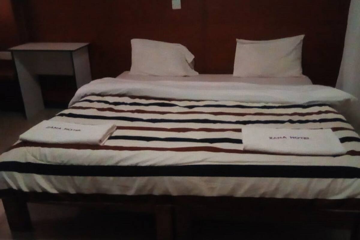 Una habitación de hotel con una cama, almohadas y una toalla doblada sobre la cama.