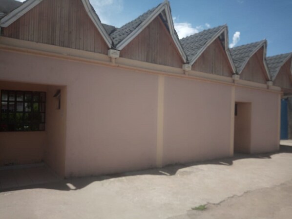 A row of wooden buildings with pitched roofs and a beige facade. - Zama Hotel (Nakuru)