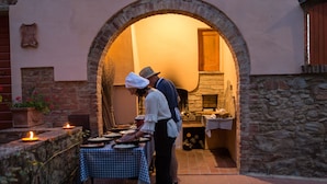 A rustic outdoor dining area with a stone wall, a checkered tablecloth, and candles. - Apartment in farmhouse, Girasole 6+1, Volterra area, San Gimignano, Pisa (Montelopio di Peccioli)