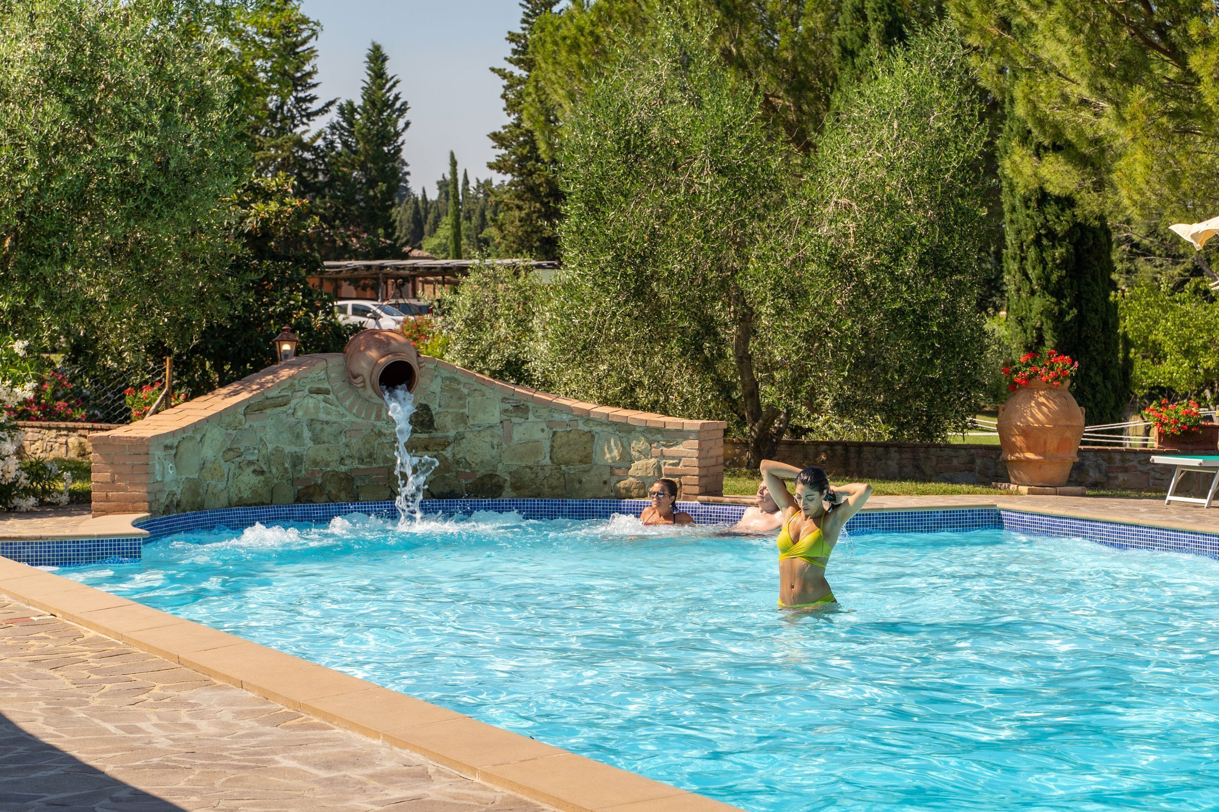 Une piscine avec un mur en pierre et un élément décoratif aquatique.