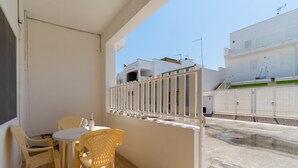 Un balcon avec une table et des chaises, une vue sur la rue et un immeuble doté de balcons.