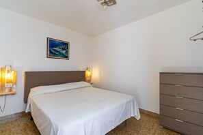 Un dormitorio con cama, lámparas de noche, cómoda y un cuadro en la pared.