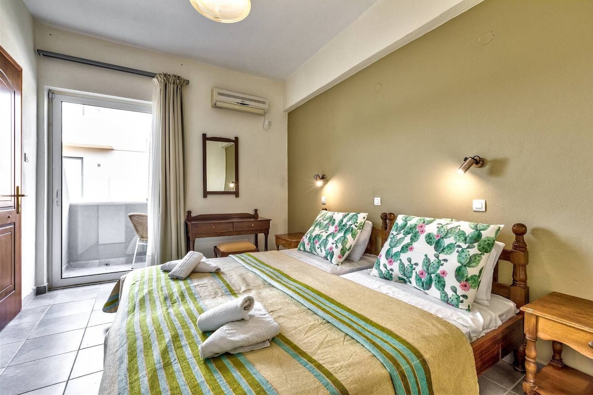 A hotel room with a bed, a desk, a chair, and a balcony.