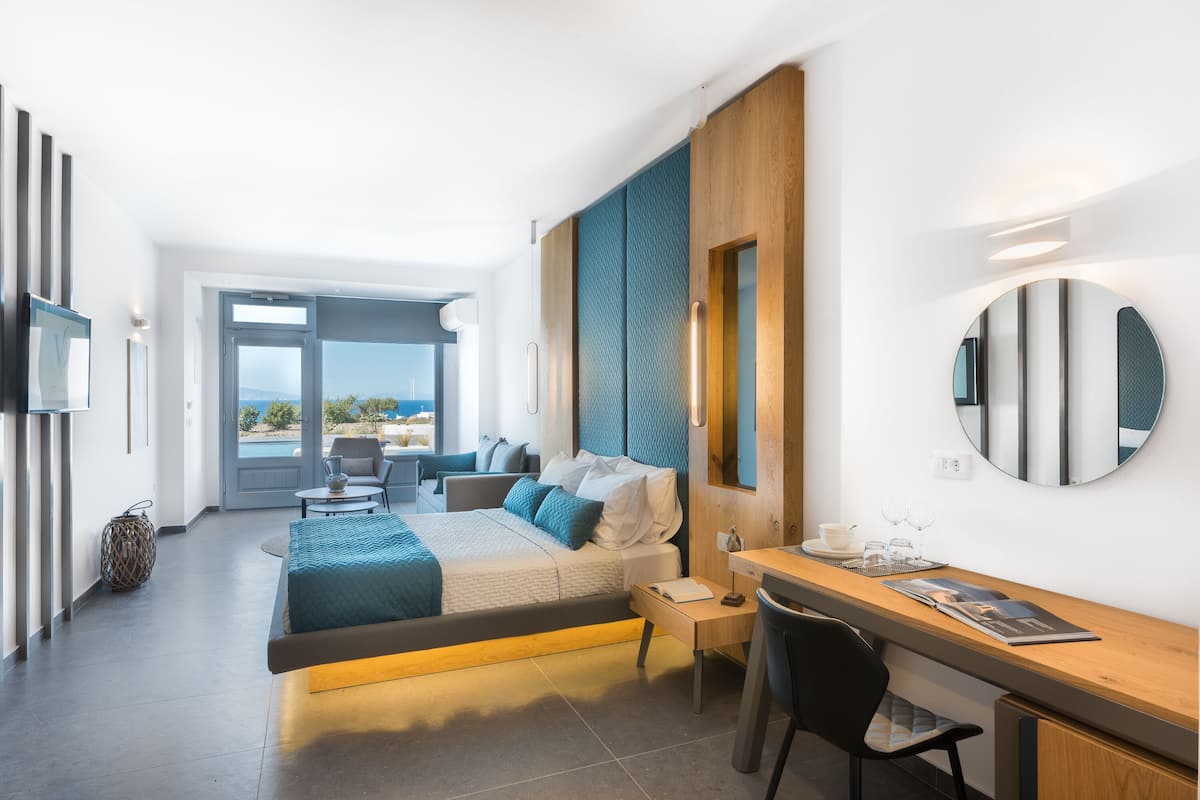 Quarto de hotel moderno com cama, escrivaninha e área de estar.