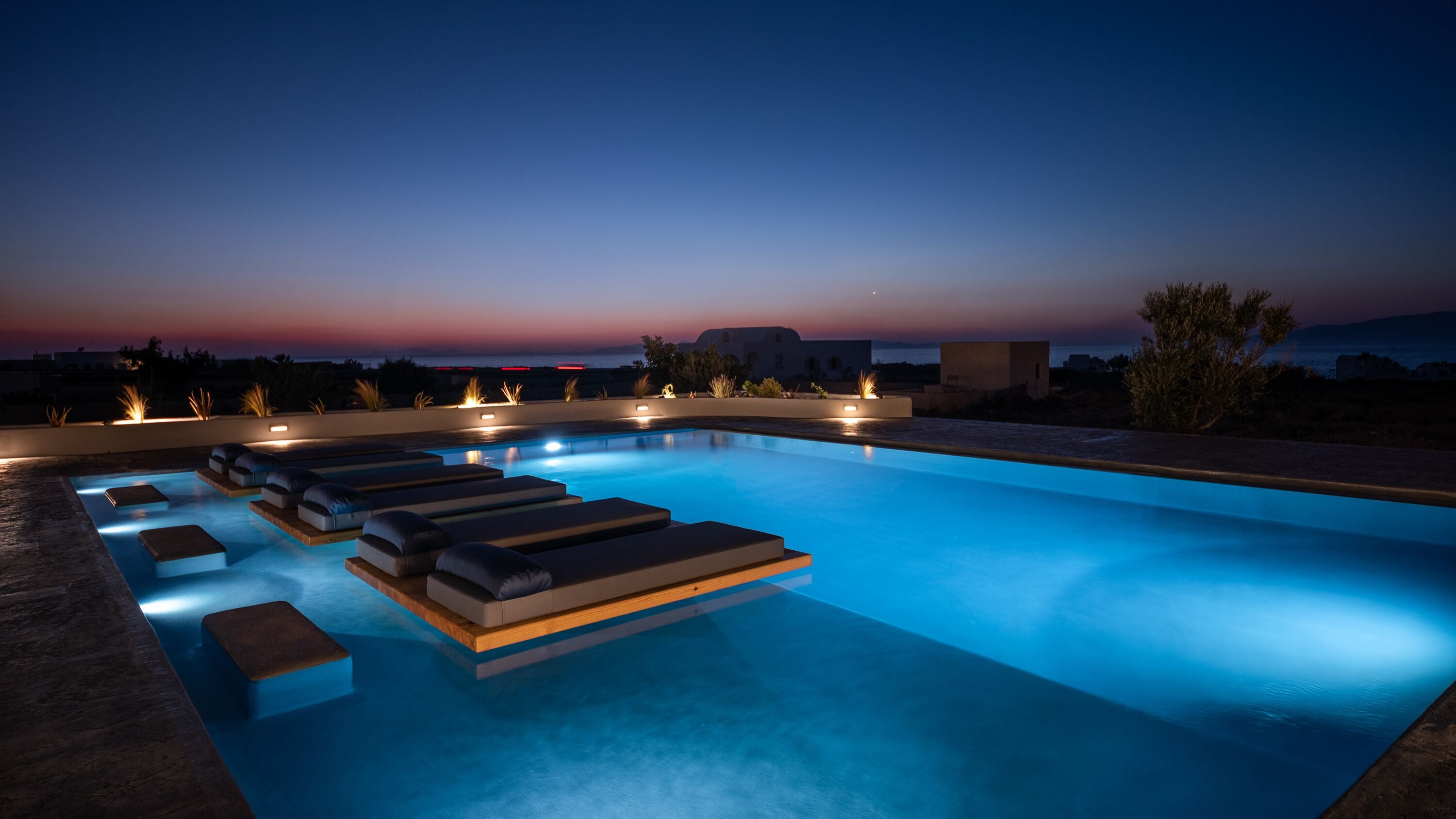 Ein Swimmingpool mit Liegestühlen und Blick auf den Sonnenuntergang.
