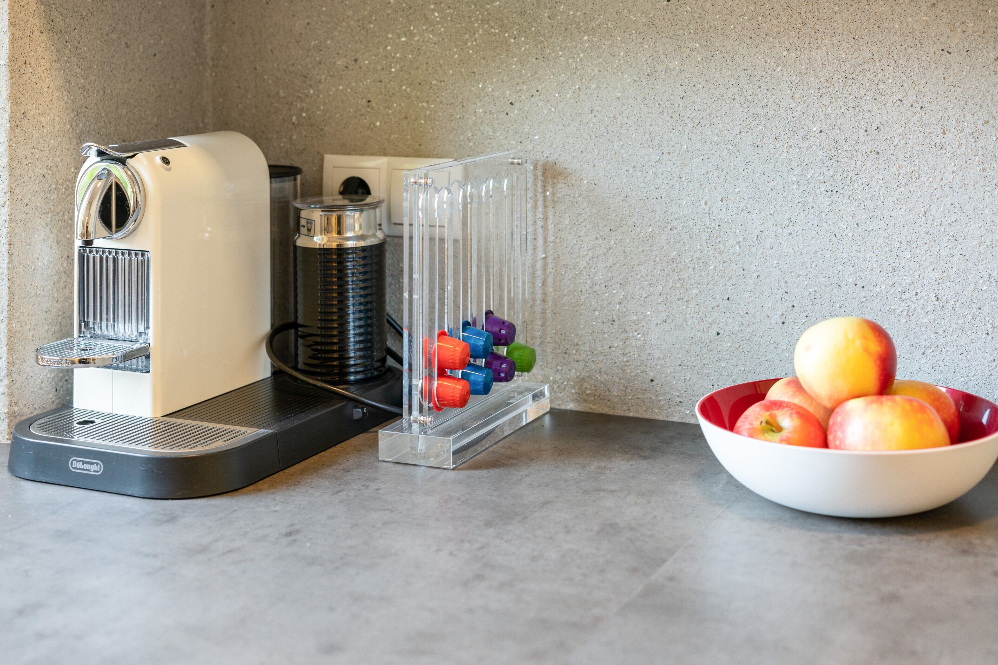 Eine Kaffeemaschine, ein Wasserspender und eine Schüssel mit Äpfeln auf einer Arbeitsplatte.