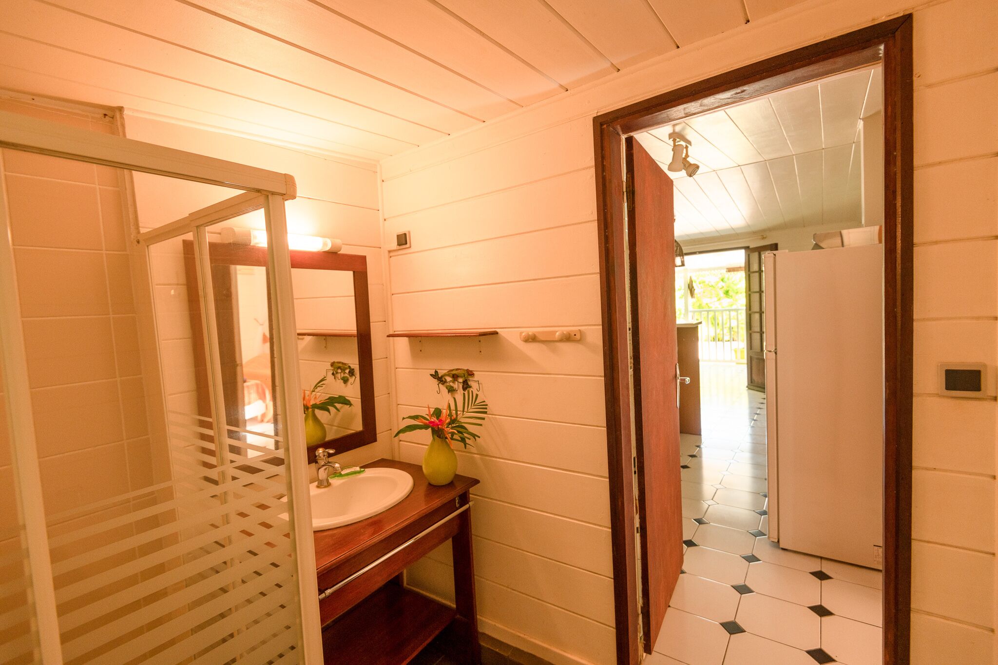 Une salle de bain avec un meuble-lavabo en bois, un évier, un miroir et une plante en pot.