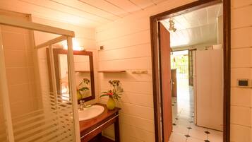 Une salle de bain avec un meuble-lavabo en bois, un évier, un miroir et une plante en pot.