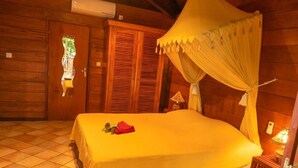A wooden room with a bed under a canopy, a tiled floor, and wooden walls. - Baobab Et Palmiers (L'Étang-Salé)