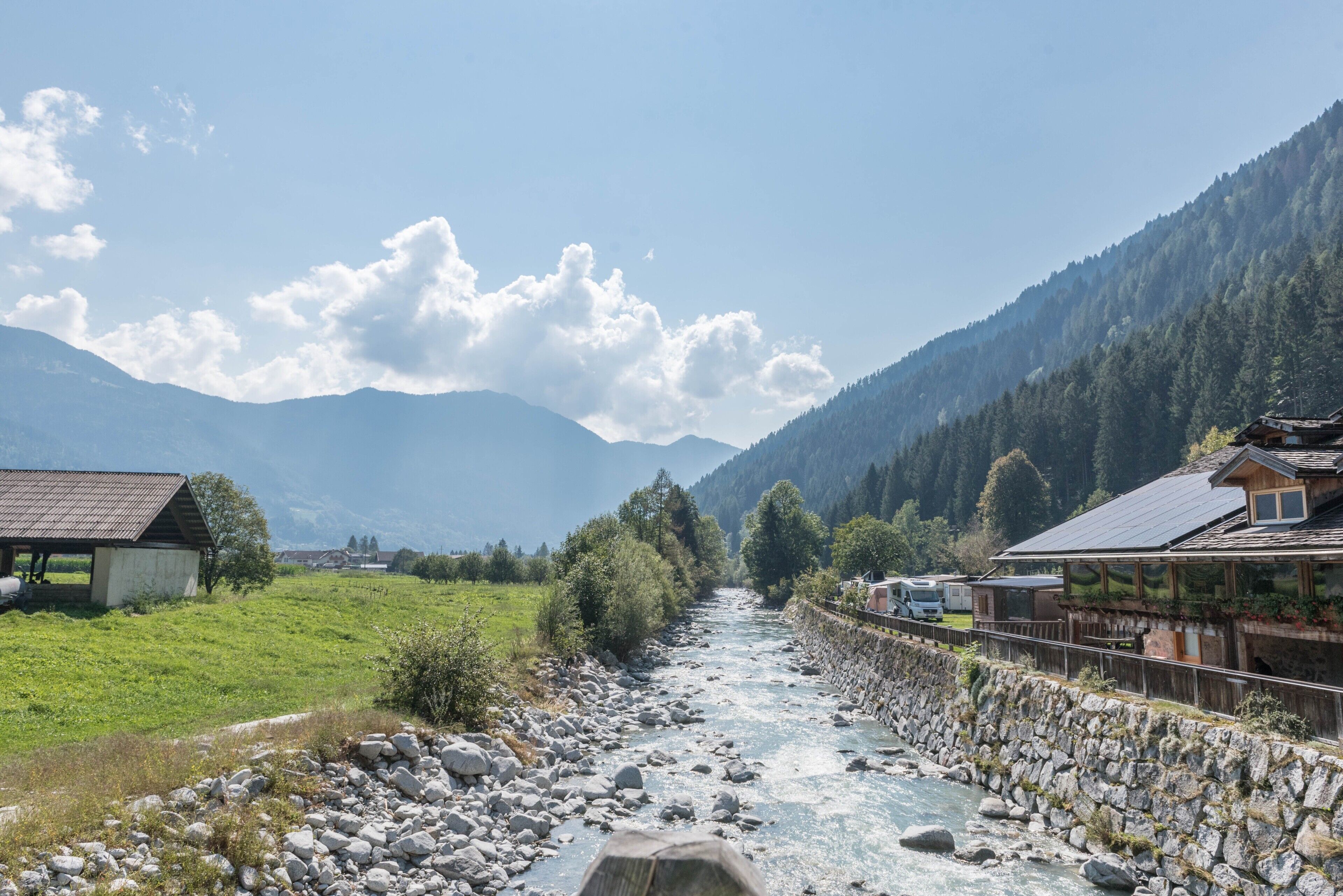 A river flowing through a mountainous area with buildings on the banks.