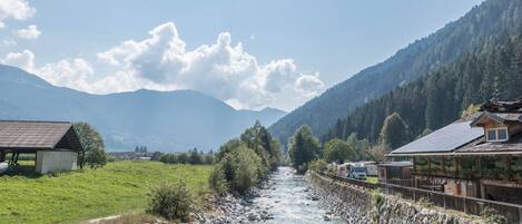 A river flowing through a mountainous area with buildings on the banks.