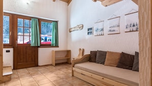A cozy room with a wooden bench, a sofa, a wooden door, and a window with curtains.