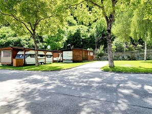 A row of RVs parked in a grassy area with a paved road in front. - Beautiful 'Adamello 13' Apartment with Wi-Fi (Pinzolo)