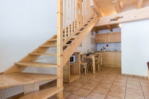 A wooden staircase leading to a kitchen with wooden cabinets and a tiled floor. - Beautiful 'Adamello 15' Apartment with Wi-Fi (Pinzolo)