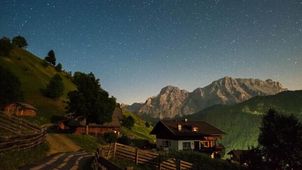 A rural mountain landscape with a house, a wooden fence, and a clear night sky. - Cosy Apartment "Confolia 1" with Wi-Fi and Mountain View (La Valle)