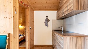 A wooden interior with a kitchenette, a bench, and a small bed. - Cosy Apartment "Confolia 1" with Wi-Fi and Mountain View (La Valle)