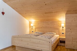 A wooden-paneled bedroom with a bed, bedside lamps, and a heart-shaped decoration.