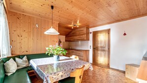A wooden interior with a dining table, green sofa, and a potted plant. - Cosy Apartment "Confolia 1" with Wi-Fi and Mountain View (La Valle)
