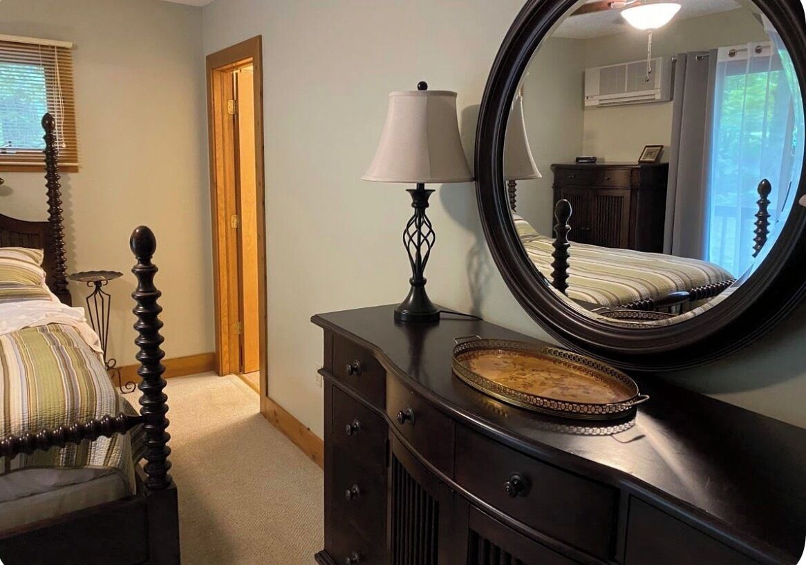 Une chambre à coucher avec un lit à baldaquin, une commode avec un miroir et une lampe.