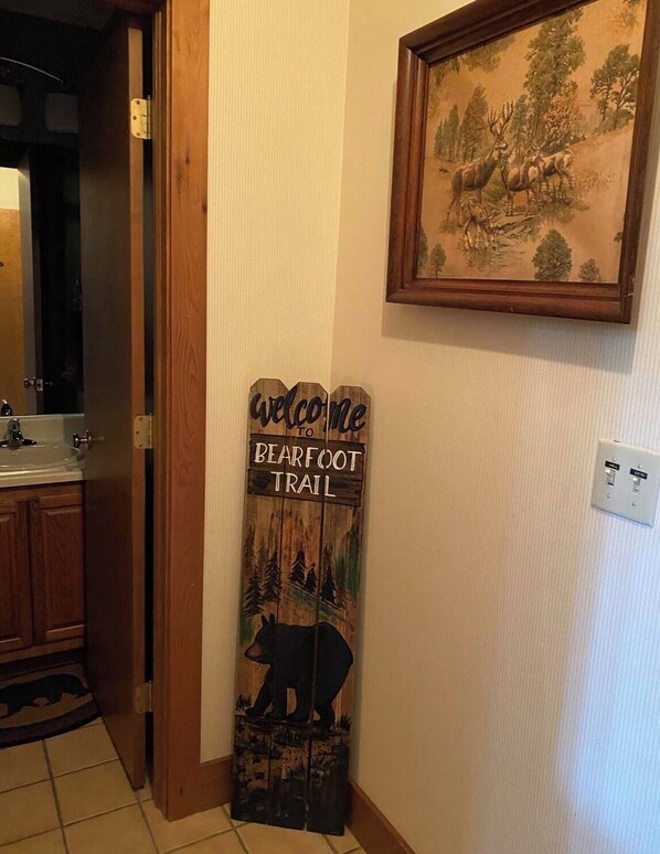 A wooden sign with a bear and forest scene, placed in a hallway with a framed picture above it. - Blue Ridge Mt retreat steps off the Appalachian Trail in Wintergreen Resort (Roseland)