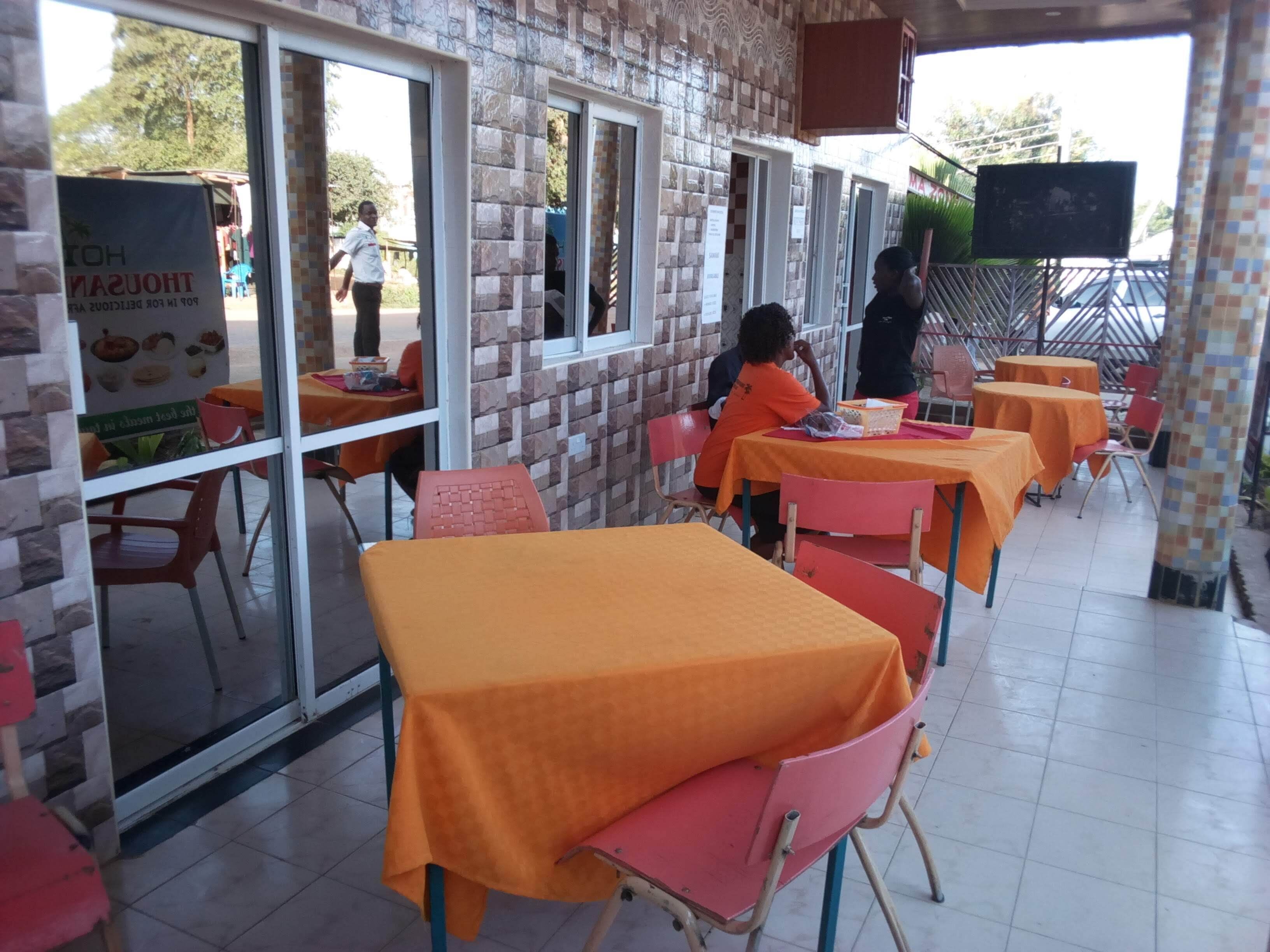 A restaurant with outdoor seating, brick walls, and a tiled floor.