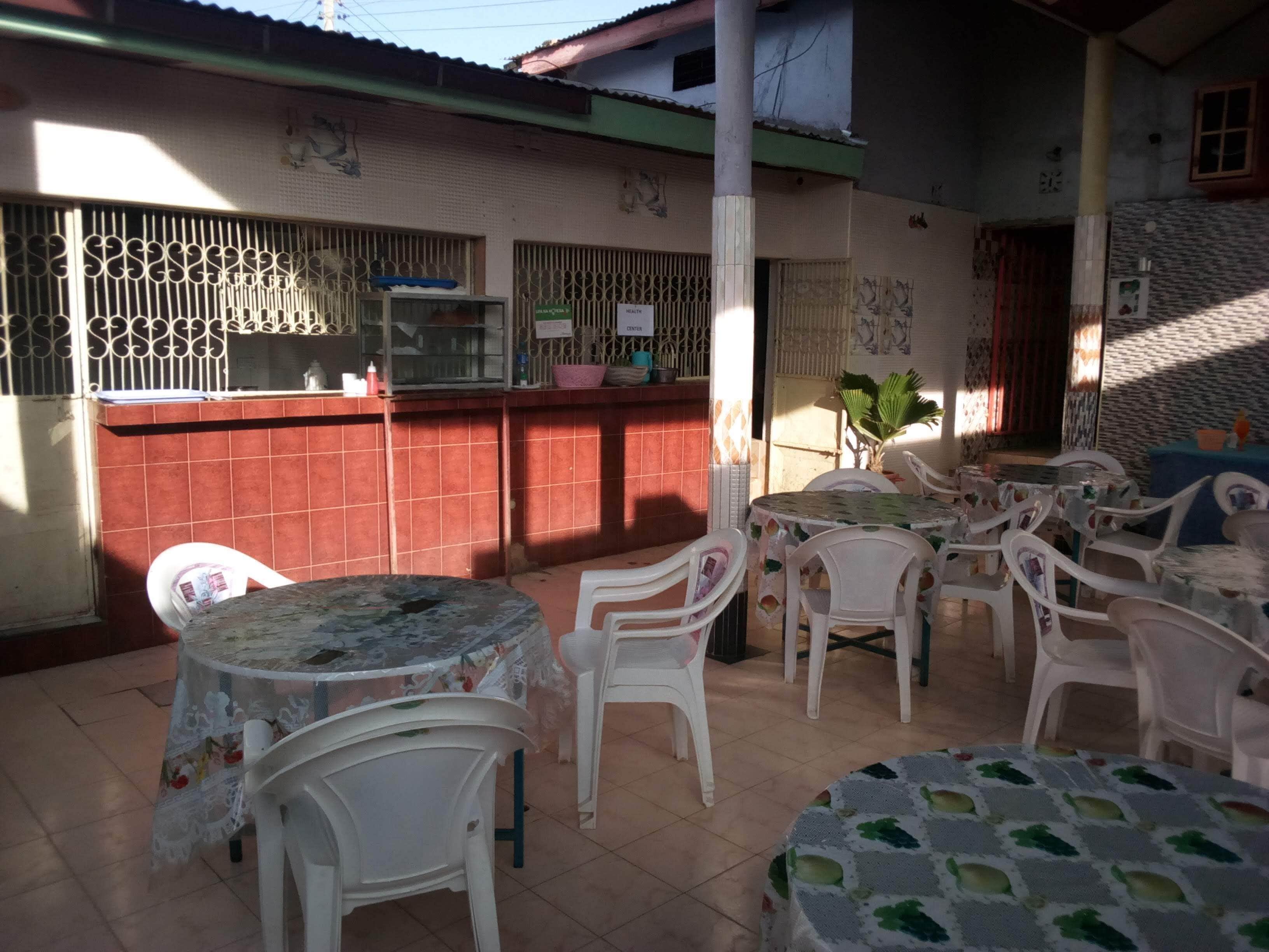 A restaurant with outdoor seating, including tables and chairs, and a kitchen area with a counter and decorative elements.